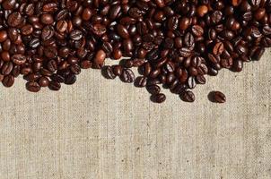 Texture of a gray canvas made of old and coarse burlap with coffee beans on it photo