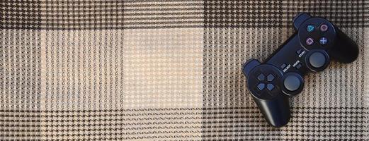 Video game controller lies on a checkered plaid photo