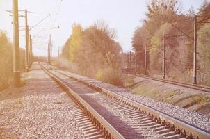 paisaje industrial de otoño. ferrocarril retrocediendo en la distancia entre árboles de otoño verdes y amarillos foto