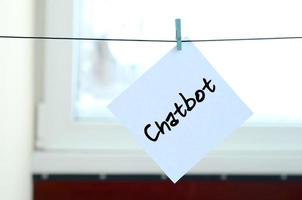 Chatbot. Note is written on a white sticker that hangs with a clothespin on a rope on a background of window glass photo