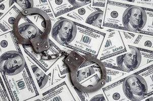 Police handcuffs lie on a lot of dollar bills. The concept of illegal possession of money, illegal transactions with US dollars. Economic Crime photo