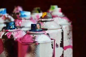 Still life with a large number of used colorful spray cans of aerosol paint lying on the treated wooden surface in the artist's graffiti workshop. Dirty and stained cans for spray art photo