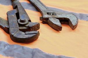 Adjustable and pipe wrenches against the background of an orange photo