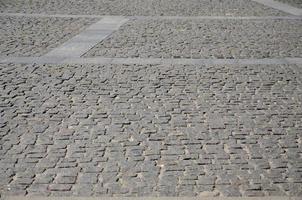 The texture of the paving slab paving stones of many small stones of a square shape under bright sunlight photo