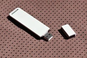 A modern portable USB wi-fi adapter is placed on the brown sportswear made of polyester nylon fiber photo