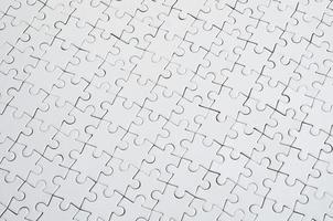 Close up texture of a white jigsaw puzzle in assembled condition. Top view. Many components of a large whole mosaic are united photo