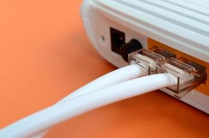 The Internet cable plugs are connected to the Internet router, which lies on a bright orange background. Items required for Internet connection photo