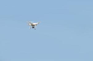 gran dron blanco flotando en un brillante cielo azul sin nubes foto