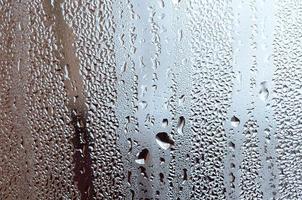 Texture of a drop of rain on a glass wet transparent background. Toned in grey color photo