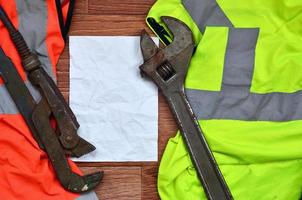 llaves ajustables y mentiras de papel de una camisa de trabajador de señal naranja y verde foto