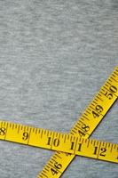 Yellow measuring tape lies on a gray knitted fabric photo