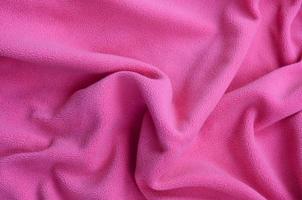 The blanket of furry pink fleece fabric. A background of light pink soft plush fleece material with a lot of relief folds photo
