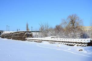 A lot of old rails and sleepers are stacked in a railway warehouse in winter. The concept of renewing a worn-out railway track photo