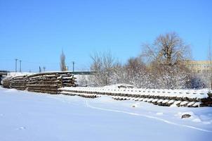 muchos rieles y durmientes viejos se apilan en un almacén ferroviario en invierno. el concepto de renovación de una vía férrea desgastada foto