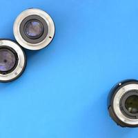 Several photographic lenses lie on a bright blue background. Space for text photo