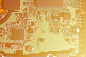 A toned macro image of a computer board with many small technological elements. Extremely shallow depth of field. Abstract technological background photo