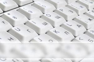 Close-up of the white computer classic keyboard with english and russian letters with copy space field photo