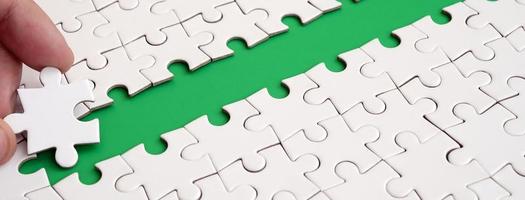 The human hand paves the way to the surface of the jigsaw puzzle, forming a green space. The concept of overcoming the difficulties on the way to success photo