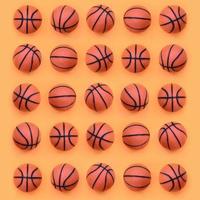 muchas pelotas naranjas pequeñas para el juego deportivo de baloncesto se encuentran en el fondo de textura del papel de color naranja pastel de moda en un concepto mínimo foto