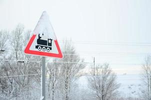 Railway crossing without barrier. A road sign depicting an old black locomotive, located in a red triangle photo