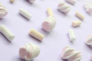 Colorful marshmallow laid out on violet paper background. pastel creative textured pattern. Perspective macro shot photo