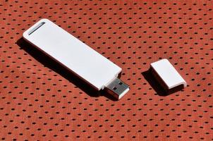 A modern portable USB wi-fi adapter is placed on the red sportswear made of polyester nylon fiber photo