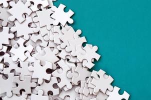 A pile of uncombed elements of a white jigsaw puzzle lies on the background of a blue surface. Texture photo with copy space for text
