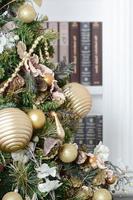 A beautiful decorated Christmas tree on the background of a bookshelf with many books of different colors. Christmas background image of the library photo