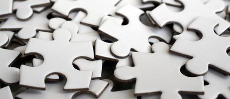 Close-up of a pile of uncompleted elements of a white puzzle. A huge number of rectangular pieces from one large white mosaic photo
