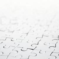 Close up of a white jigsaw puzzle in assembled state in perspective. Many components of a large whole mosaic are united photo