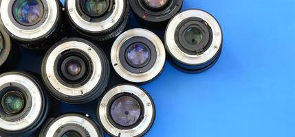 Several photographic lenses lie on a bright blue background. Space for text photo