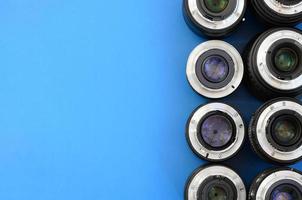 Several photographic lenses lie on a bright blue background. Space for text photo