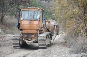 agregado de cantera con maquinaria pesada. Excavadora de oruga con retroexcavadora que conduce a la cantera del sitio de construcción foto