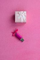 Brilliant pink usb memory card with a pink bow lies next to a small gift box in pink with a small bow on a blanket of soft and furry light pink fleece fabric. Classic female gift memory card design photo