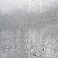 textura de una gota de lluvia sobre un fondo transparente húmedo de vidrio. tonificado en color gris foto