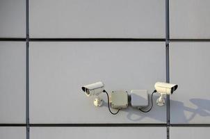 White surveillance camera built into the metal wall of the office building photo