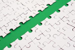 The green path is laid on the platform of a white folded jigsaw puzzle. Texture image with copy space for text photo