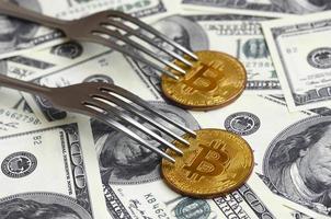 Bitcoin getting New Hard Fork Change, Physical Golden Crytocurrency Coin under the fork on the dollars background. Blockchain Transaction System Crisis Concept photo