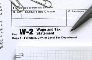 The pen and notebook on the tax form W-2 Wage and Tax Statement. The time to pay taxes photo