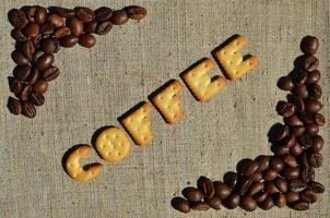 Coffee. The word from the edible letters lies on the gray canvas with coffee beans photo