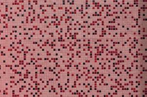 The texture of the wall, decorated with a mosaic of various small square tiles. Abstract pattern of ceramic tiles on the wall photo