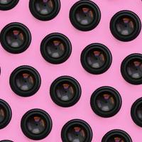 A few camera lenses with a closed aperture lie on texture background of fashion pastel pink color paper in minimal concept. Abstract trendy pattern photo