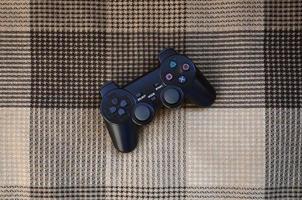 Video game controller lies on a checkered plaid photo