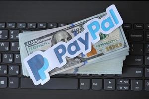 TERNOPIL, UKRAINE - SEPTEMBER 6, 2022 Payoneer paper logotype lies on black laptop with US dollar bills. Payoneer is American financial services company provides online money transfer photo