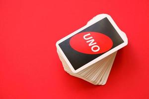 TERNOPIL, UKRAINE - MAY 15, 2022 Many colorful UNO game cards on red background. UNO is an American shedding-type card game that is played with a specially printed deck photo