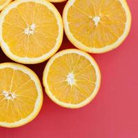Top view of a several orange fruit slices on bright background in red color. A saturated citrus texture image photo