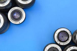 Several photographic lenses lie on a bright blue background. Space for text photo