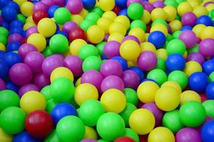 muchas bolas de plástico de colores en una piscina para niños en un parque infantil. patrón de primer plano foto