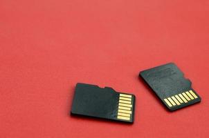 Two small micro SD memory cards lie on a red background. A small and compact data and information store photo