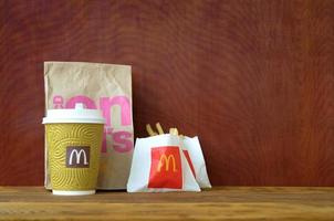 kharkov, ucrania - 9 de diciembre de 2020 bolsa de papel para llevar mcdonald's y comida chatarra en mesa de madera foto